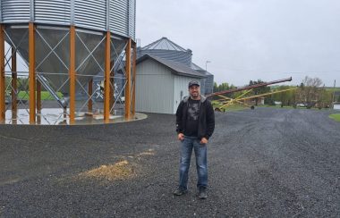 Un homme se tenant devant un silo à grains lors d'une journée pluvieuse