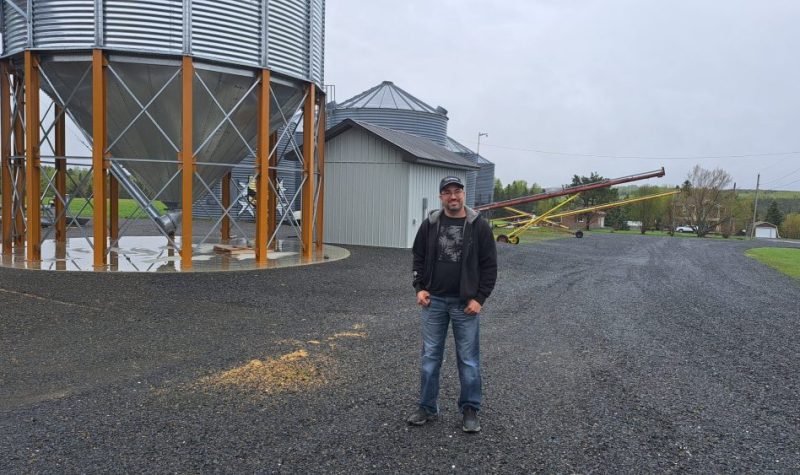 Un homme se tenant devant un silo à grains lors d'une journée pluvieuse