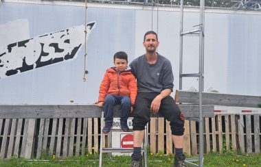 Un papa et son fils à l'extérieur, assis côte-à-côte sur une poutre de bois pour une photo