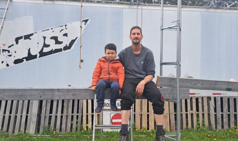 Un papa et son fils à l'extérieur, assis côte-à-côte sur une poutre de bois pour une photo