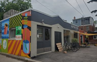 Karma Co-op's building. A mural is on one side of the wall. Bikes are parked out front of the enterance.