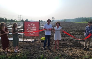 A couple cuts a red ribbon held by their three children in front of a sign for their new vineyard.