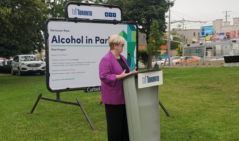 Toronto city councillor Shelley Carroll behind a podium with a huge sign saying 'Alcohol in Parks'