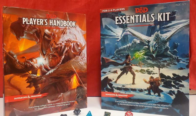 A dungeons and dragons players hand book and Essentials Kit against a red background with dice inbetween them