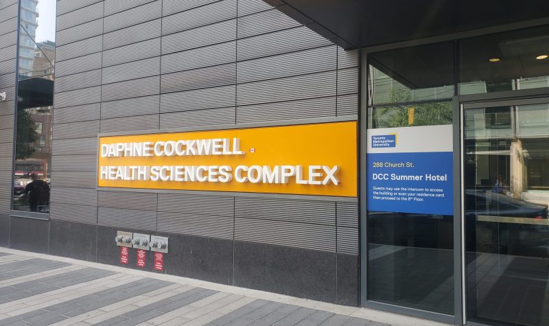 Black wall with an orange sign that reads 'Daphine Cockwell Health Sciences Complex'