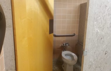 A accesibility stall in a washroom with poor lighting