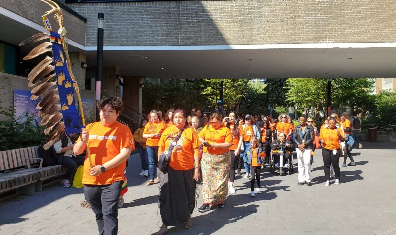 A group of people in orange shirts march on the Toronto Metropolitian University campus