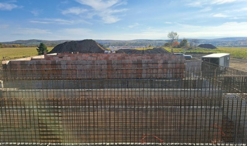 Un réservoir d'eau potable en construction, on peut voir des grilles de fers et des murs de ciment, pendant une journée ensoleillée.