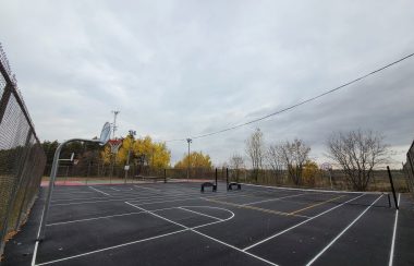 A freshly asphalted outdoor court with basketball and pickleball nets.