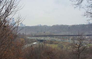 Cars driving on the Don Valley Parkway with tree around the border of the photo