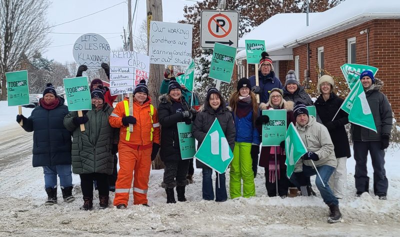 A group of teachers on the picket line in snow suits.