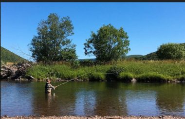 Un homme pêchant dans une rivière par une belle journée ensoleillée.