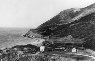 Une ancienne maison et une ancienne grange au bord de la mer au pieds des montagnes.