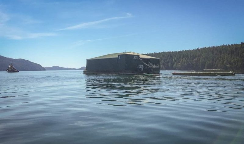A tugboat tows a large square shed through the Discovery islands