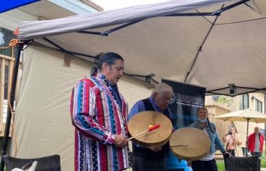 Indigenous male singing with a hand drum in his hand