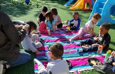 Children sitting and enjoying a picnic outside their early learning centre