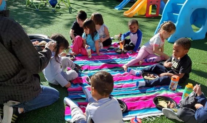 Children sitting and enjoying a picnic outside their early learning centre