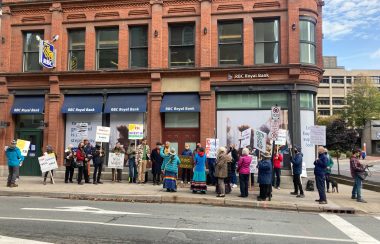 Face au bâtiment de la RBC, des personnes sont assemblées sur le trottoir, on y voit aussi des représentants des autochtones.