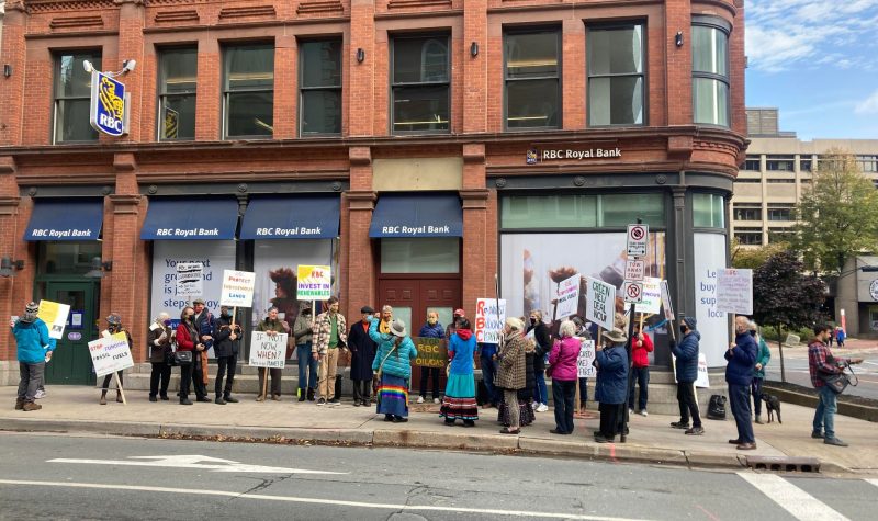 Face au bâtiment de la RBC, des personnes sont assemblées sur le trottoir, on y voit aussi des représentants des autochtones.