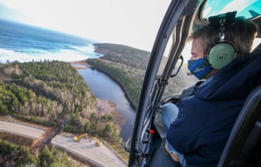 Un homme à bord d'un hélicoptère surveille les réparations à une route endommagée.