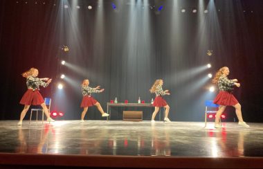 Quatre jeunes filles dansent sur une scène en costume.