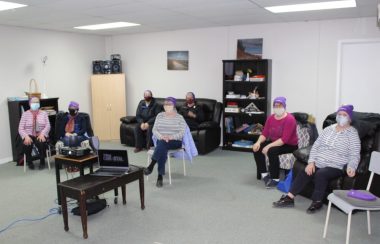 Des dames habillées en violet assises dans une salle.