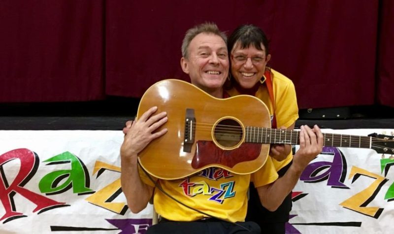 Un homme et une femme portant des chandails jaunes et des cravates rouges et tenant une guitare.