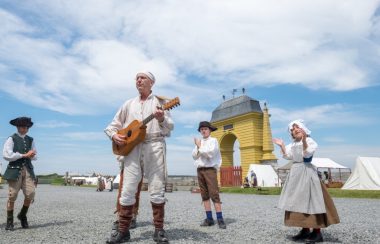 Un homme et des enfants en costumes d'époque jouant de la musique et dansant dans la rue.