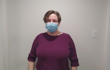 Pictured is Rachel Lambie, curator for the museum, standing against a white background wearing a bright purple shirt.