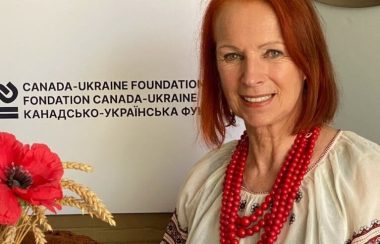 Pictured is Bohdana Zwonok with the Canada Ukraine Foundation logo behind her. She is sitting at a table with some of the meal items that will be available.