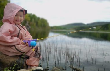 Un jeune enfant habillé en rose tentant sa chance à la pêche.