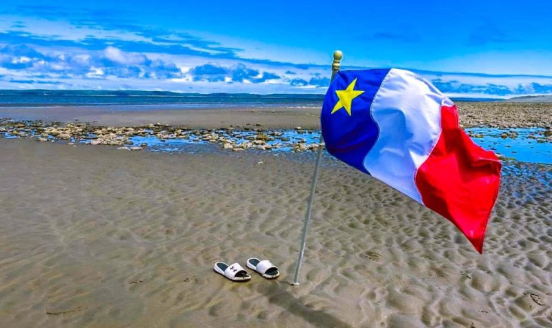 Un drapeau acadien sur une plage.