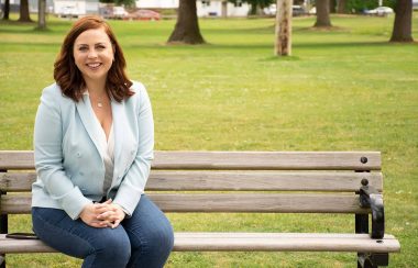 A press photo of City Council Candidate Alex Mitchell sitting on a park bench.