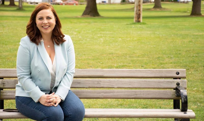 A press photo of City Council Candidate Alex Mitchell sitting on a park bench.