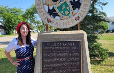 Emma Iafolla-Lafrenière se tient à côté de l'emblème du village de Falher.