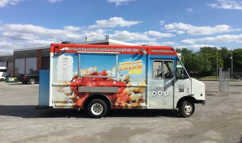 Food truck with funnel cake picture on side in front of a building in a parking lot