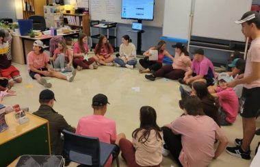 Des élèves portant des chandails roses assis par terre.