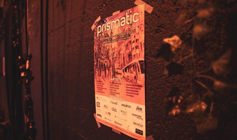 Une affiche indiquant les différents sponsors et date du festival est affichée sur un mur sombre