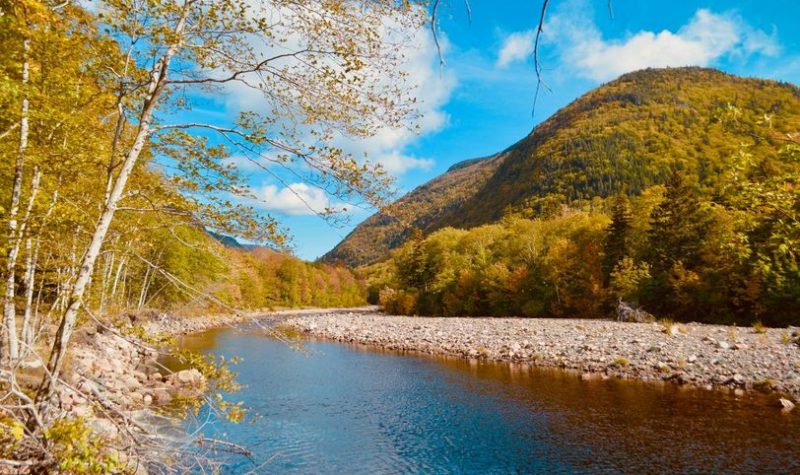 Une rivière au pieds des montagnes aux couleurs d'automne.