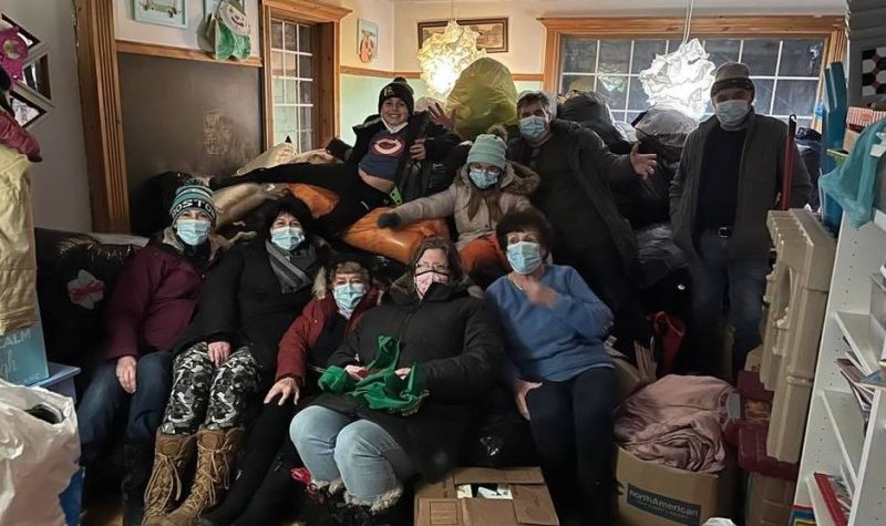 Pictured is Logan and volunteers sitting on a number of bags filled with donated items.