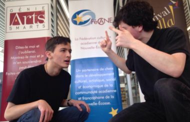 Deux jeunes hommes habillés en noir en avant de banderoles.