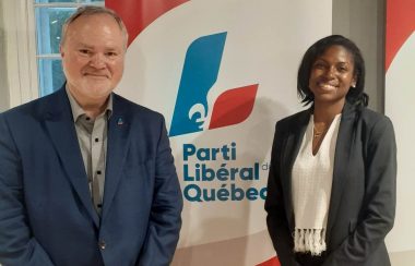 À gauche, André Pratte, vêtu de veston bleu. À droite, Madwa-Nika Cadet, vêtue d'un chandail blanc et d'un veston noir. Au milieu, une bannière arborant le logo du Parti libéral du Québec.