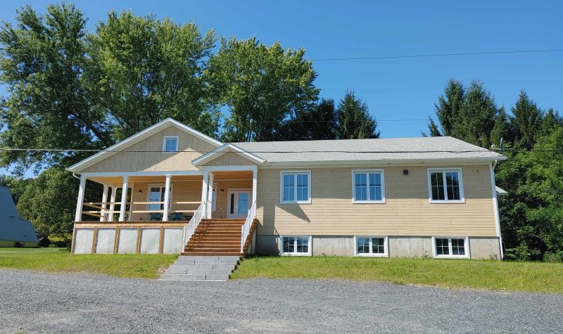 A yellow single story building with front porch and with white accents.