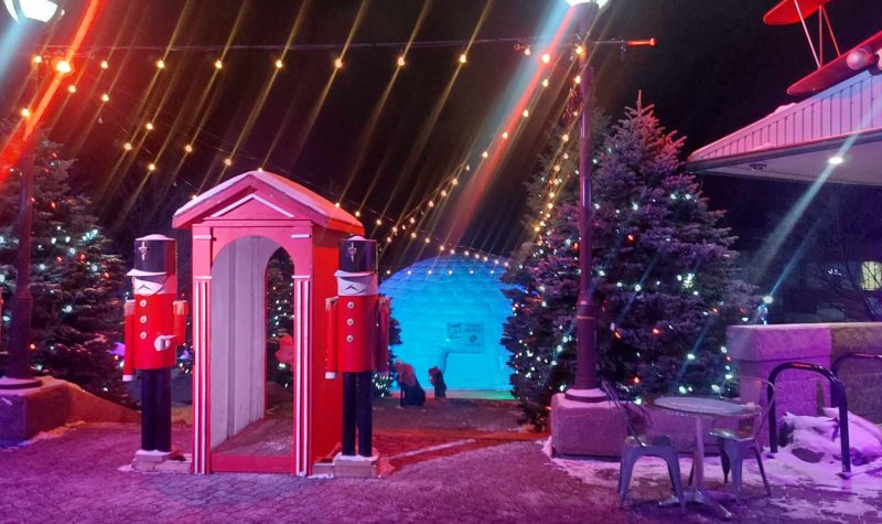 Des décorations de Noël à l'extérieur comprenant un gros sapin illuminé, un igloo gonflable géant et des soldats de casse-noisette géant