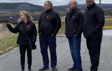 Immigration Minister Gerry Byrne (far right) meets with the Housing Minister and NLHC executives to talk about solutions to housing issues in Corner Brook. All four are wearing dark coats. It's a dark cloudy day in Corner Brook.