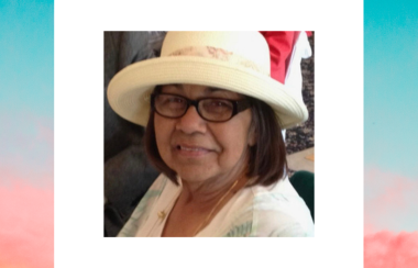 A woman smilig. She is wearing black glasses and a white hat. A colourful sky outlines the picture of the woman.