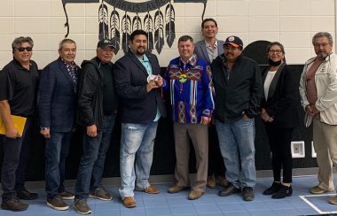 Minister Wilson meets with Chief Silas Yellowknee, member of council Ken Alook and other members of Bigstone Cree Nation. Chief Yellowknee stands second to the left, while member of council Alook and Minister Wilson ‘cut’ an AITE card in the middle of the group.