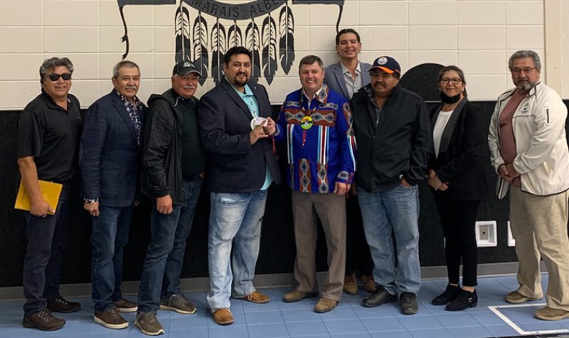 Minister Wilson meets with Chief Silas Yellowknee, member of council Ken Alook and other members of Bigstone Cree Nation. Chief Yellowknee stands second to the left, while member of council Alook and Minister Wilson ‘cut’ an AITE card in the middle of the group.