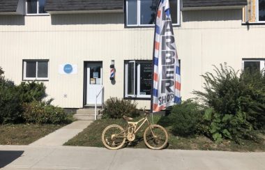A photo of a children's bicycle, spray painted in gold, sits outside of Sweeny T's Barbershop in Mount Forest.