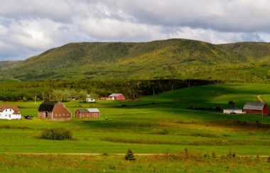 Trois maisons et trois granges dans une vallée.